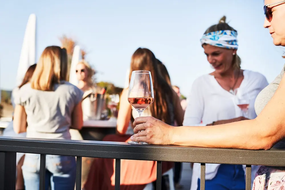 Glas Rosé auf dem Geländer, Gäste im Hintergrund