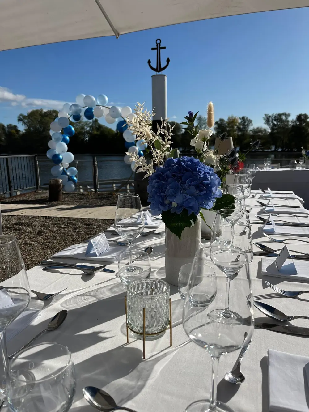 Festlich gedeckte Hochzeitstafel mit blauer Hortensie, dahinter Ballonbogen und Anker – Hochzeit am Rhein in Oestrich-Winkel